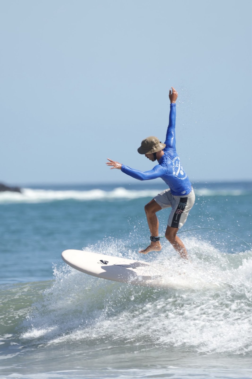 Surfer carving with energy on a clean wave under a blue sky