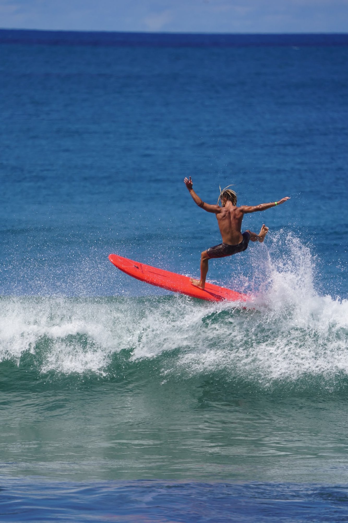 Dylan surfing a wave on a red board in the open ocean at Playa Venao, Panama